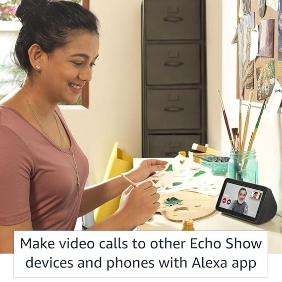 A woman uses her Echo Show to video call friends, smiling as she connects with them.